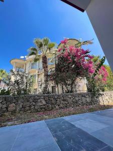 a building with a palm tree and a stone wall at Dalaman Ege Pam Residence in Dalaman