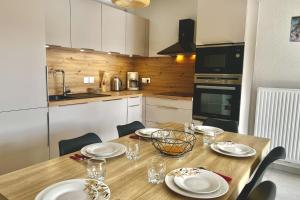 una cocina con una mesa de madera con platos y vasos. en T3 apartment with balcony in Briançon, en Briançon