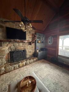 ein Wohnzimmer mit einem Steinkamin und einem Deckenventilator in der Unterkunft Luxury Cabin HotTub, Hiking, Fire Pit, Game Room in Ellijay