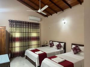 a bedroom with two beds and a ceiling at Lahiru Airport Villa in Andiambalama
