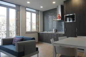 a living room with a blue couch and a kitchen at Casinhas Dom Afonso by Hotel Dom Afonso in Monção