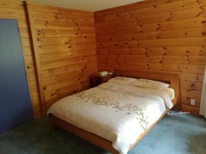 ein Schlafzimmer mit einem Bett in einer Holzwand in der Unterkunft Beaver Farm House in Bombay