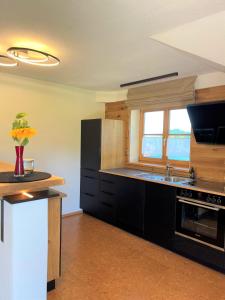 a large kitchen with black cabinets and a window at Traumplatz im Allgäu in Rettenberg