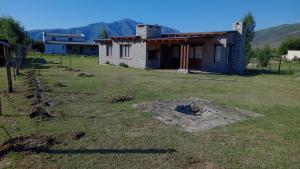 a house in a field next to a building at Las Piedras in Tafí del Valle