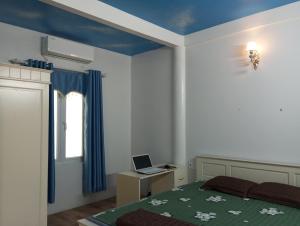 a bedroom with a bed and a laptop on a desk at Đức Tới Farmstay in Ho Tô