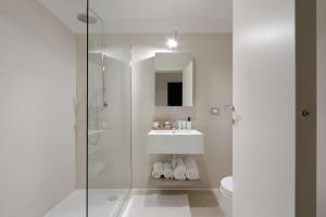 ein weißes Badezimmer mit Waschbecken und Dusche in der Unterkunft Portopiccolo Apartments in Sistiana