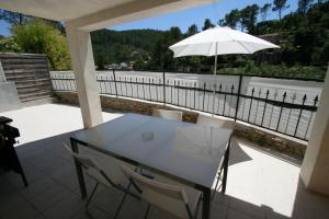 a white table and chairs on a balcony with an umbrella at Villa du Sud in Solliès-Toucas