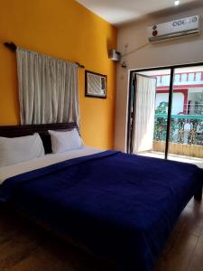 a bedroom with a large blue bed with a window at Calangute Rocks Inn in Calangute +22 photos