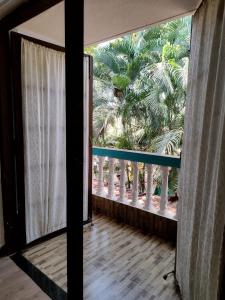 a balcony with a view of a palm tree at Calangute Rocks Inn in Calangute
