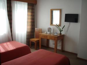 Cette chambre comprend deux lits et un bureau avec un miroir. dans l'établissement Hotel Residencial Ermida dos Remédios, à Praia da Vitória