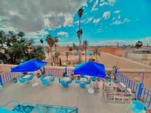 a patio with blue umbrellas and tables and chairs at Hostel Essassi 23 in Marrakesh