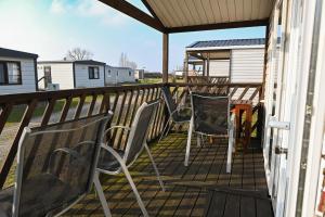 une terrasse avec deux chaises et une maison dans l'établissement Ferienpark Süderstapel - Eiderlodge 1, à Süderstapel