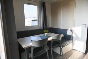 una sala da pranzo con tavolo, sedie e una finestra di Ferienpark Süderstapel - Eiderlodge 3 a Süderstapel