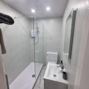 a white bathroom with a shower and a sink at Cove Bay 1 Bed Flat in Largs
