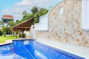 a villa with a swimming pool and a stone wall at Perfect Villa with Pool Access and Close to the Beach in Playa del Carmen