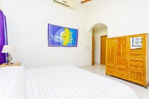 a bedroom with a large white bed and a wooden cabinet at Perfect Villa with Pool Access and Close to the Beach in Playa del Carmen
