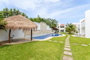 a villa with a swimming pool and a straw umbrella at Perfect Villa with Pool Access and Close to the Beach in Playa del Carmen