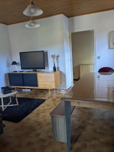 a living room with a flat screen tv and a table at Camping Les Berges Du Doux in Colombier-le-Vieux