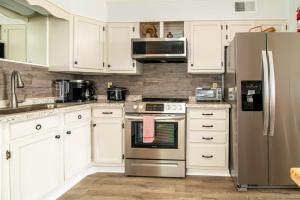 una cucina con armadi bianchi e frigorifero in acciaio inossidabile di Windy Waves Top Location w Pool a Myrtle Beach