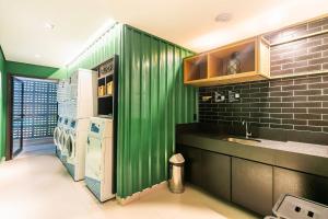 a green kitchen with a sink and a refrigerator at Go Vila Mariana - Studio 7 min. a pé do Metrô in Sao Paulo