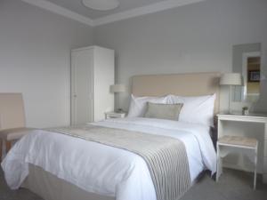 - une chambre blanche avec un grand lit blanc et des oreillers blancs dans l'établissement Westwinds Guestlodge, à Galway