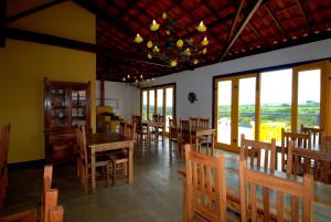uma sala de jantar com mesas, cadeiras e janelas em Pouso do Alferes em Santo Antônio do Leite