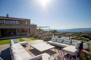 un patio con sofás blancos, una mesa y una casa en Luxury 4-bedroom villa - pool, en Gordes