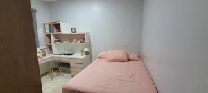 Habitación pequeña con cama rosa y escritorio. en Casa inteira, en Rio Verde