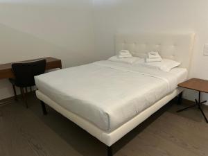 a white bed in a room with a desk and a chair at Moderno appartamento a Tenero in Tenero