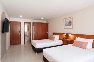 a hotel room with two beds and a television at Hotel MS Chipichape in Cali