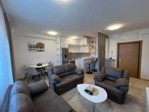 a living room with couches and a table and a kitchen at Lux apartment Rose in Kragujevac