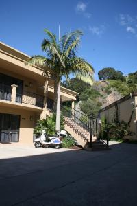 a palm tree and a scooter parked in front of a building at Tuscany Villas Whakatane in Whakatane