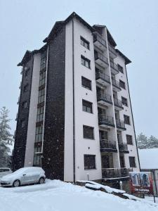 a snow covered building with a car in front of it at Studio Snežana in Zlatibor