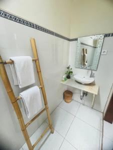 a white bathroom with a sink and a mirror at With Love Bali Homestay in Tegalalang