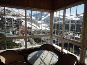 einen Tisch und Stühle vor einem Fenster mit schneebedeckten Bergen in der Unterkunft Hotel Nevasur in Sierra Nevada