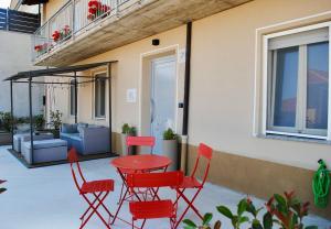 a patio with red chairs and a table and a couch at Cascina Montè in Guarene