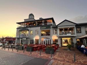a building with tables and chairs in front of it at Hermanus Waterfront Apartment in Hermanus