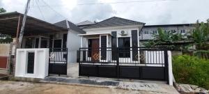 坤甸Assa House的一栋白色的房子，大门是黑色的