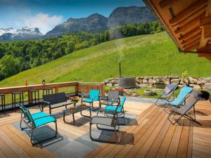 a deck with chairs and a bench with mountains in the background at Lodge La Source - OVO Network in Les Clefs