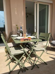 a green table and chairs with food and wine at Penthouse Apartment A due passi dal Mare in Alghero