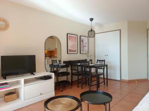 a living room with a tv and a table with chairs at T1 Bis avec piscine vue golf et montagnes in Arcangues