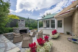 eine Terrasse mit Korbstühlen und einem Steinkamin in der Unterkunft Arrowtown Lodge in Arrowtown