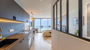 a kitchen with black and white cabinets and a living room at L'Edelweiss du Lac in Tresserves