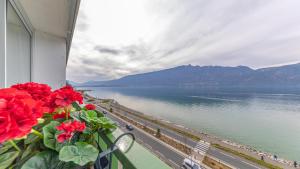 a balcony with red flowers and a view of the water at L'Edelweiss du Lac in Tresserves