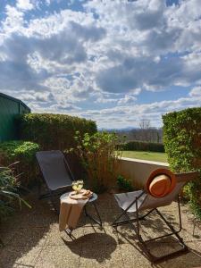 two chairs and a table on a patio at T1 Bis avec piscine vue golf et montagnes in Arcangues