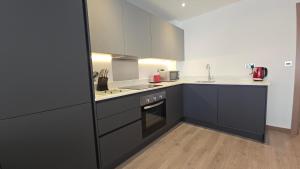a kitchen with black and white cabinets and a sink at Roomspace Serviced Apartments - Harvest Lane in Thames Ditton