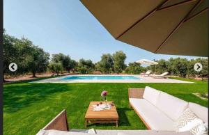 a backyard with a pool and a table and an umbrella at Modern trulli with a beautiful new pool in Ceglie Messapica