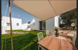 a wooden table and chairs under an umbrella on a yard at Modern trulli with a beautiful new pool in Ceglie Messapica