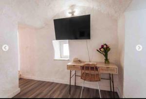 a room with a table with a tv on the wall at Modern trulli with a beautiful new pool in Ceglie Messapica
