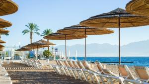 a row of chairs and umbrellas on a beach at דירת גן מפנקת בסיסייד 100 מטר מהים - By Edomlux in Eilat